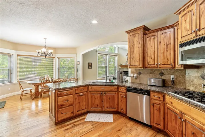 Kitchen featuring wood-finish flooring, wood cabinetry, granite countertops, and a tile backsplash