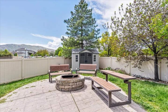 Stoned-paver patio area featuring a built-in stone fire pit, surrounded by benches and a matching picnic table