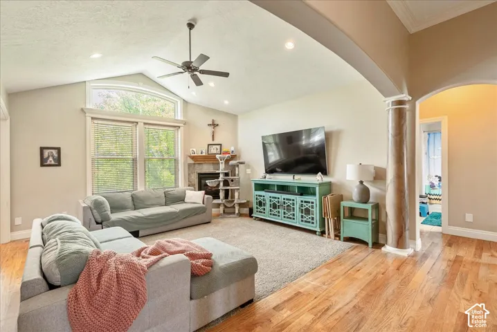 Spacious living area featuring vaulted ceilings, a ceiling fan, recessed lighting, and large windows with an arched transom