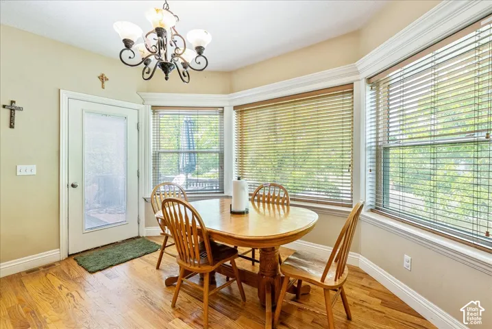 Bay window with multiple windows, wood-finish flooring, a white-framed door with a frosted glass panel, and a decorative chandelier