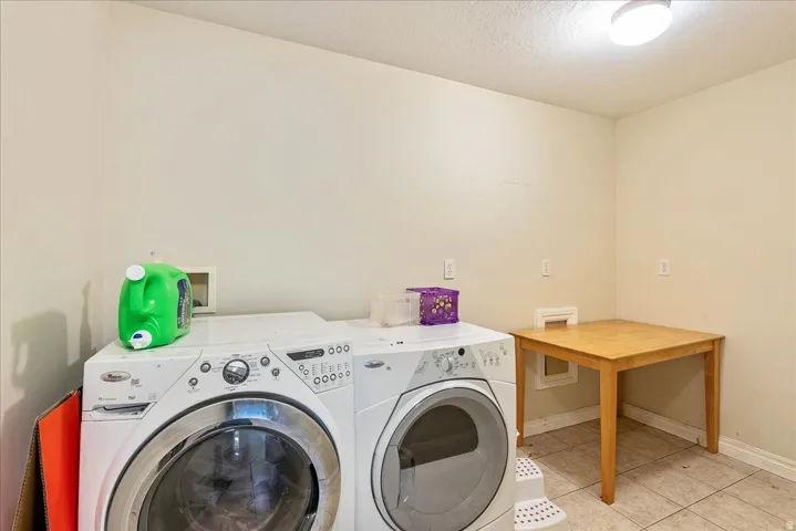 Dedicated utility space featuring light-toned walls and tile flooring