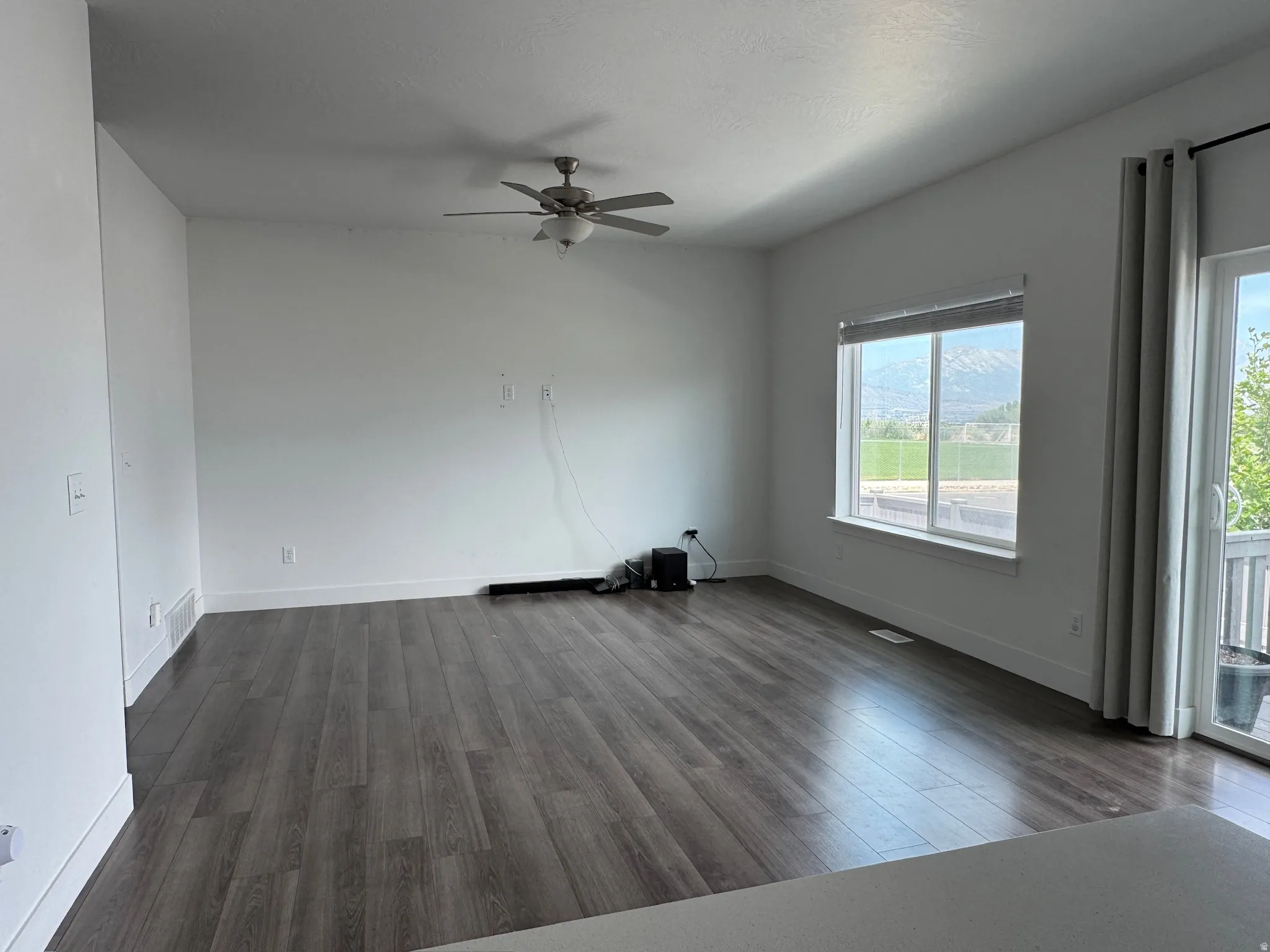 Spacious room featuring wood-finish flooring, a contemporary ceiling fan, and a large window offering mountain scenery