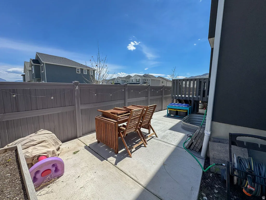 Paved patio area featuring a privacy fence, elevated wooden deck, and a raised garden bed
