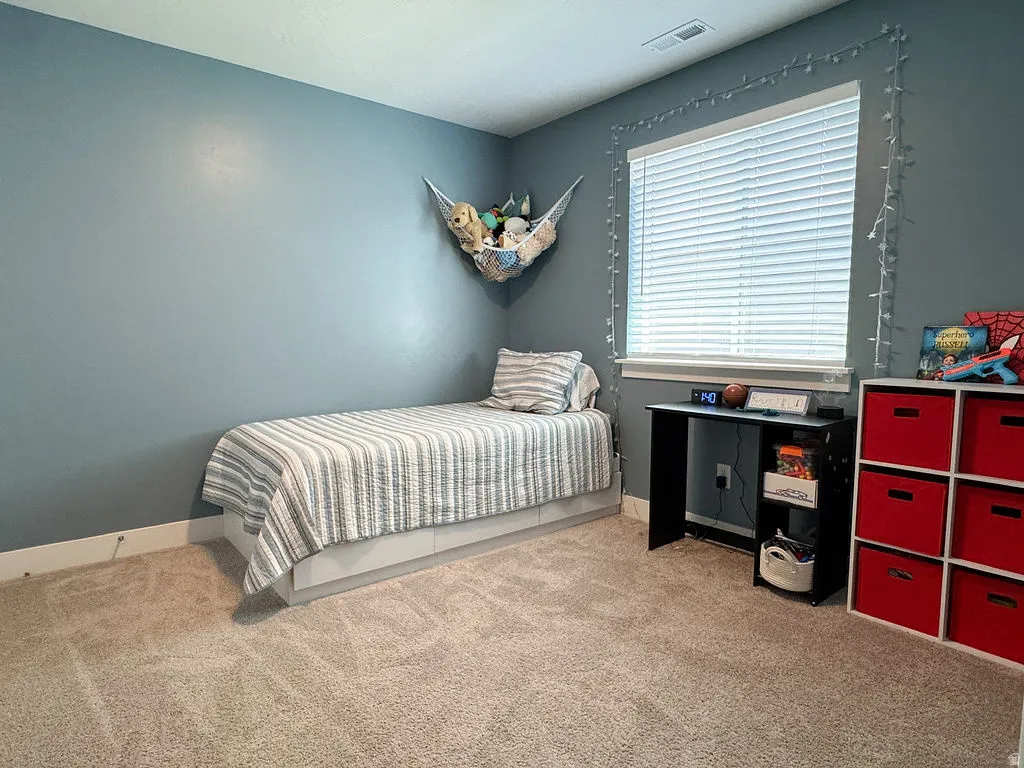 Carpeted room featuring a window with horizontal blinds, light blue walls, and white trim