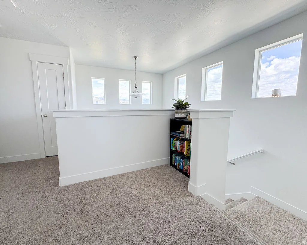 Carpeted landing area featuring a white balustrade, integrated shelving, and multiple high-set windows