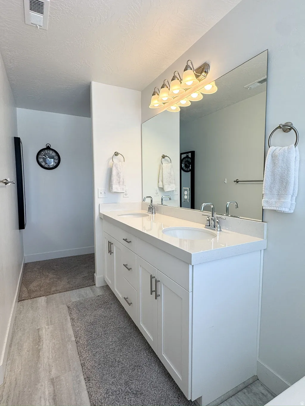 Double vanity featuring white cabinetry with brushed nickel hardware, integrated sinks, and a light-toned countertop