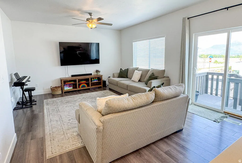 Open-concept living area with wood-finish flooring, a ceiling fan, and white walls