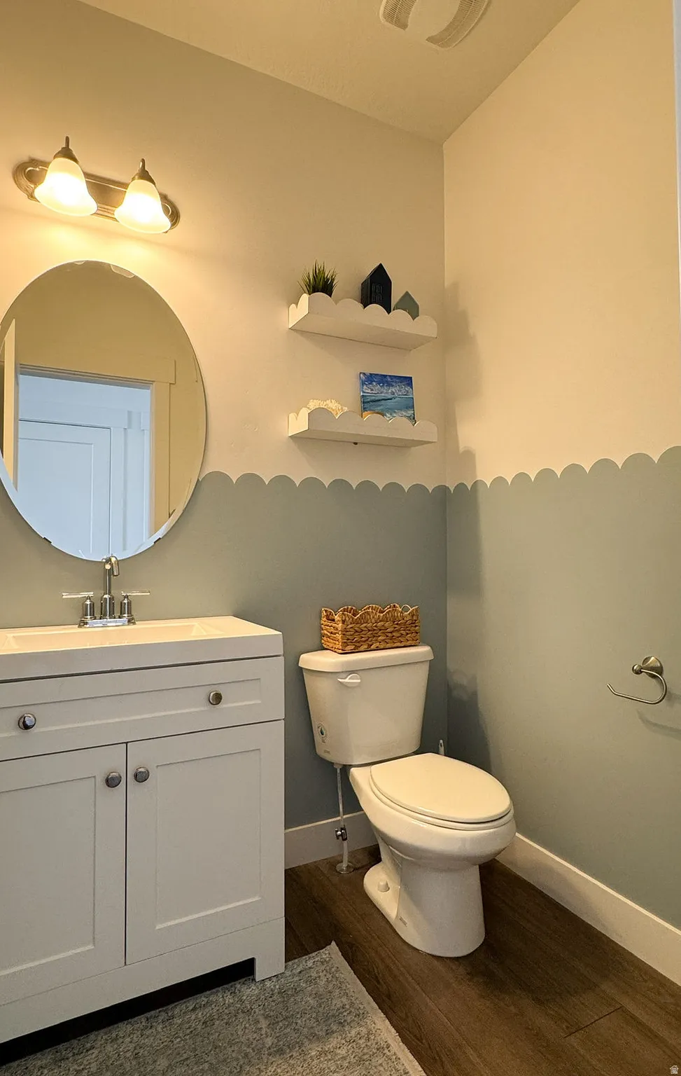 Bathroom featuring a white vanity with a rectangular sink, a polished chrome faucet, and an oval mirror