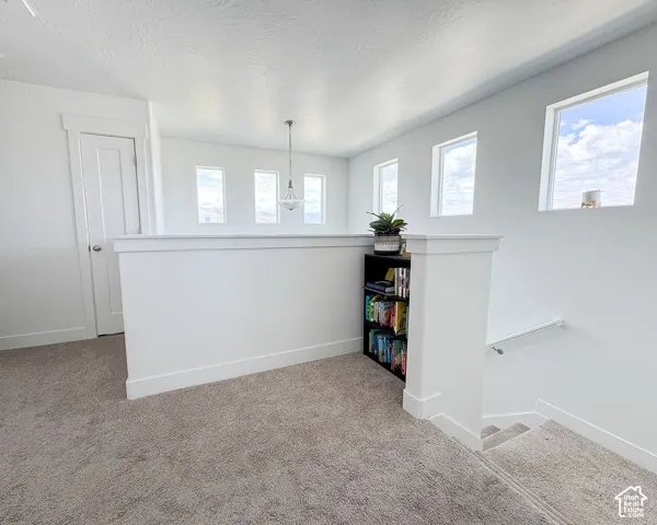 Carpeted landing area featuring a white balustrade, integrated shelving, and multiple high-set windows