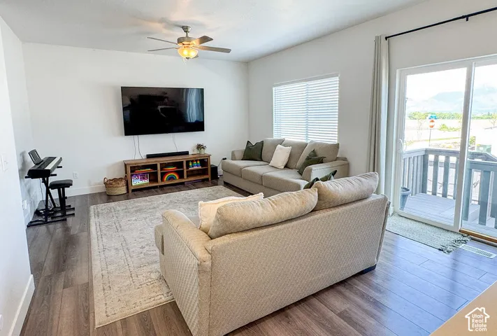 Open-concept living area with wood-finish flooring, a ceiling fan, and white walls