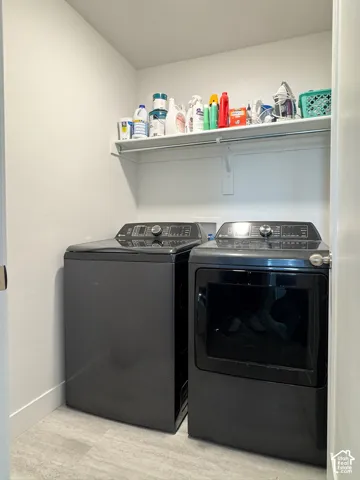 Dedicated laundry area featuring a white wire shelf, light-toned walls, and grey tile flooring
