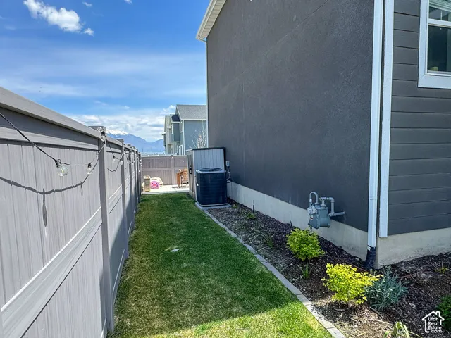 Fenced side yard with a manicured lawn, established landscaping, and a stucco and siding exterior