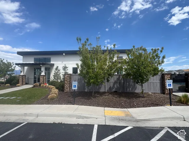 Contemporary white-paneled building with dark trim, featuring an inviting entrance with stone-clad columns and a dark pergola