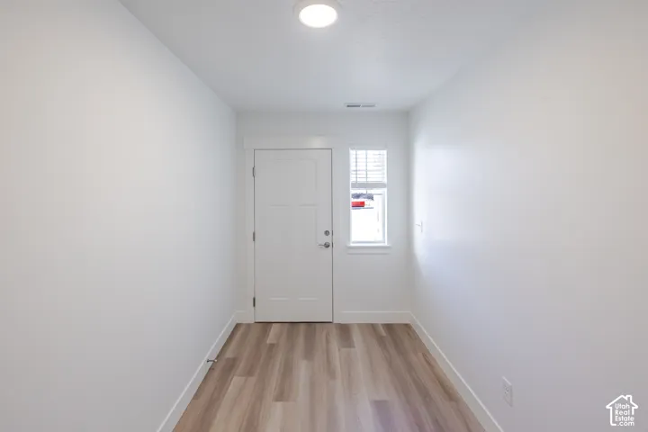 Entryway featuring wood-finish flooring, a solid-panel door with craftsman-style trim, and a vertical window