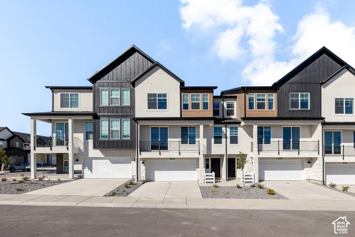 Contemporary townhome exterior featuring multi-toned siding, vertical board-and-batten accents, private elevated balconies with metal railings, and attached multi-car garages