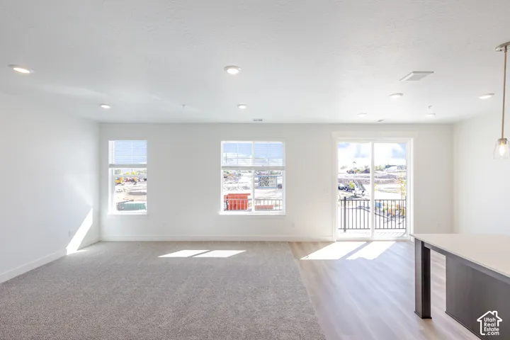 Interior space featuring recessed lighting, multi-tone wood-finish flooring, wall-to-wall carpeting, dual-pane windows, and a sliding glass door providing external access