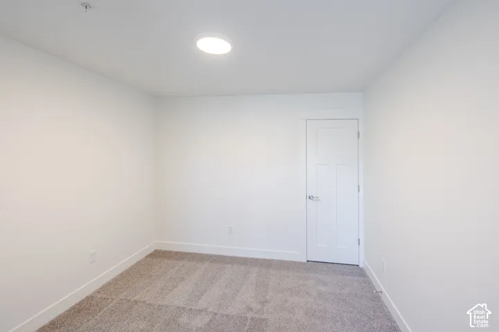 Neutral-toned carpeting, minimalist white wall finish, recessed ceiling lighting, and a three-panel interior door with satin-finish hardware