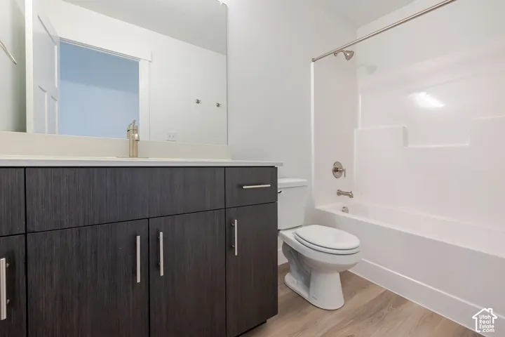 Dark-toned wood-finish cabinetry, white countertop with an integrated basin, brushed nickel hardware, expansive vanity mirror, and a white tub-shower surround