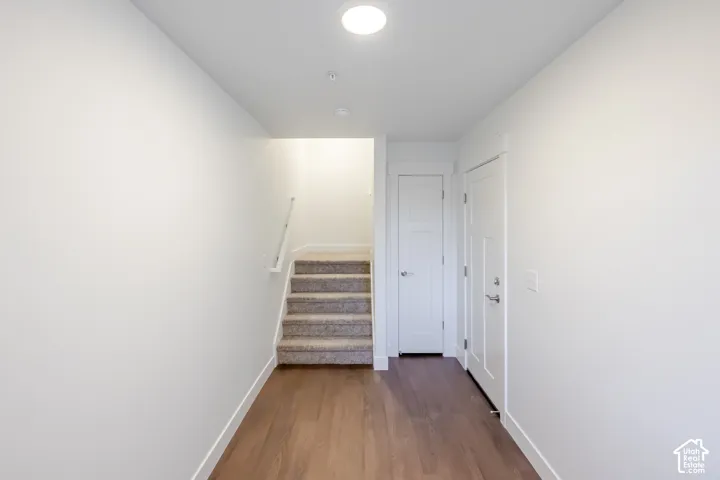 Recessed ceiling lighting, wood-finish flooring, white trim, paneled interior doors, and a carpeted staircase with a white handrail