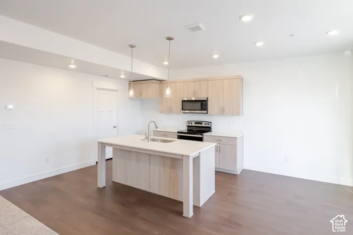 Kitchen island with integrated sink, stainless steel faucet, and pendant lighting