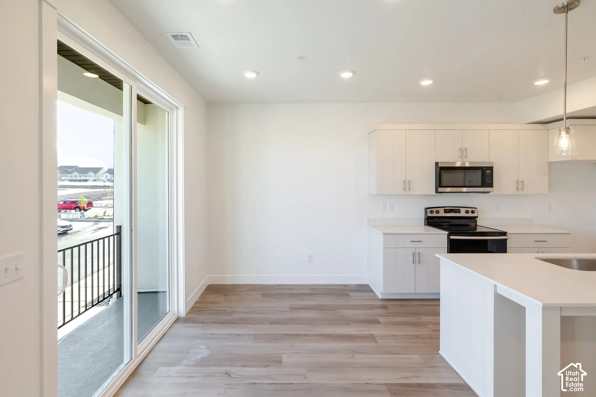 Modern kitchen featuring white cabinetry, stainless steel microwave, and white countertops