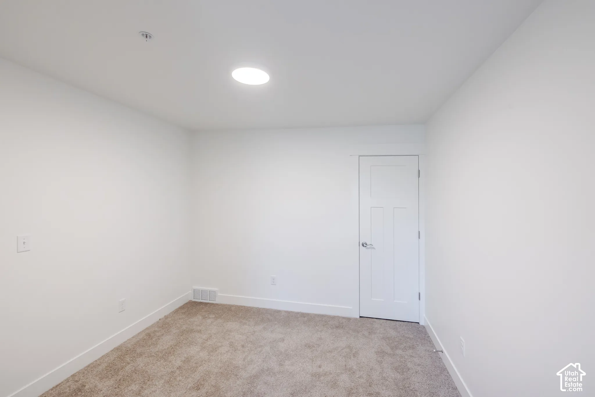 Recessed ceiling light, white interior door, light-toned carpet, and white walls