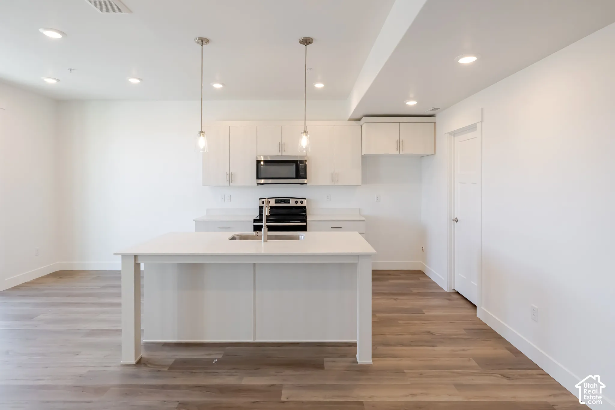 Open-concept kitchen with a central island, recessed lighting, and wood-finish flooring