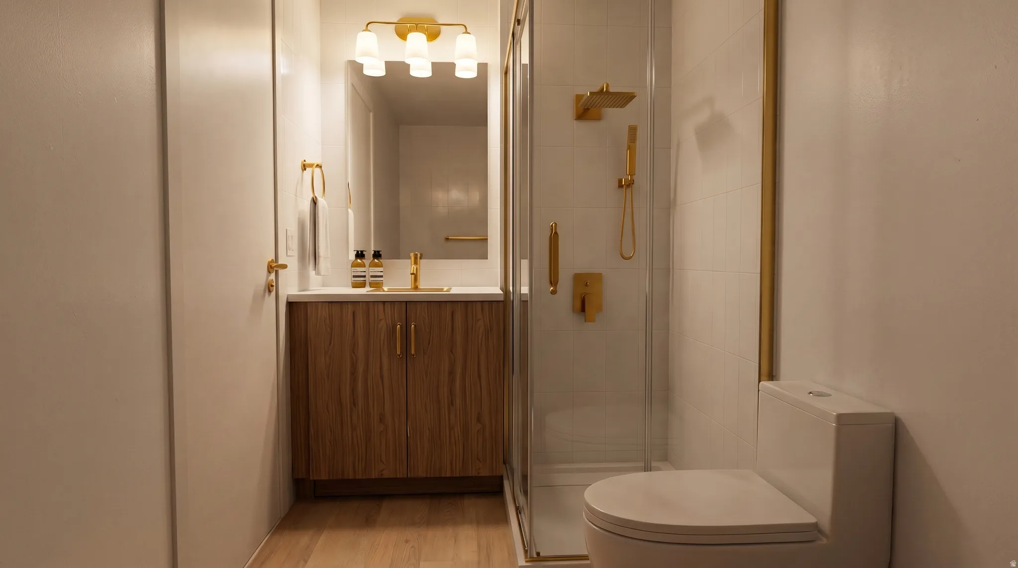 Bathroom featuring a full vanity with wood-finish cabinetry and a light-toned countertop, a glass-enclosed shower with gold-finish fixtures, and a white toilet
