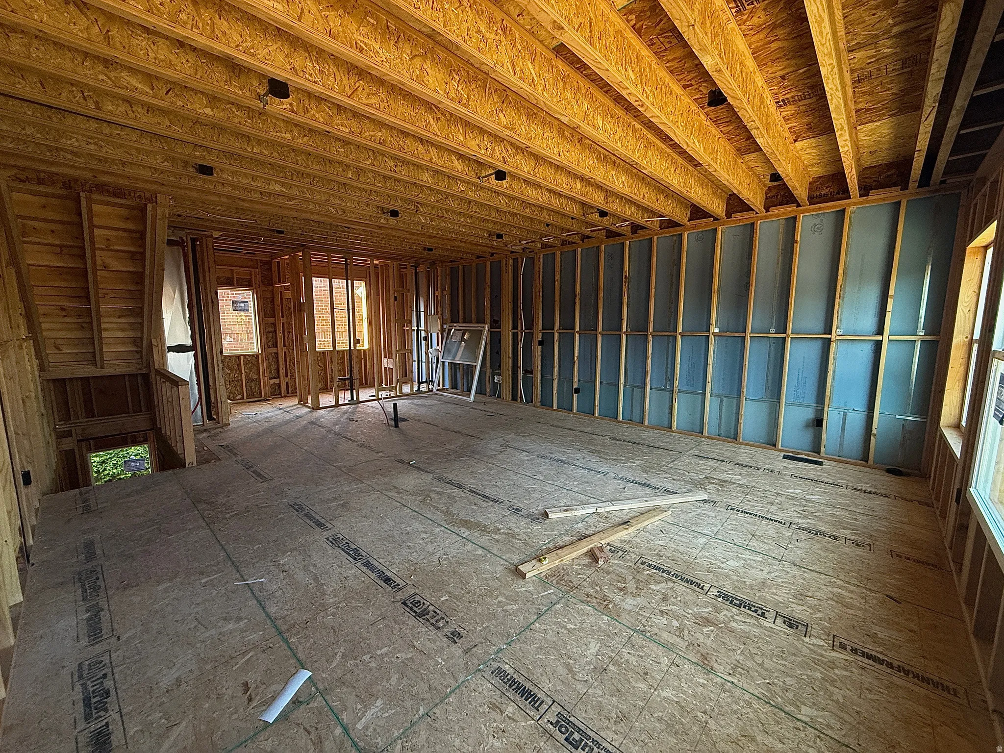 Expansive room featuring exposed wood framing, subflooring, and ceiling joists