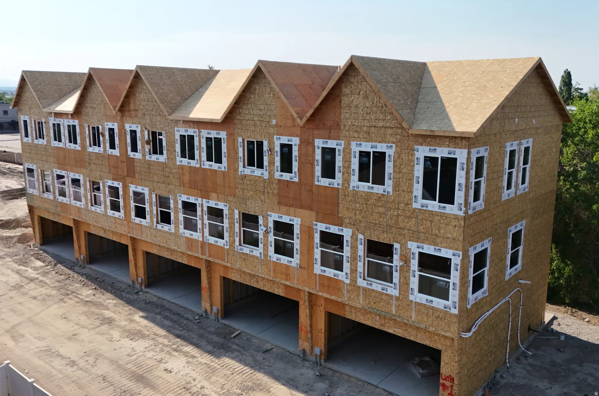 New construction multi-unit building featuring multiple levels, numerous windows, and individual ground-level garage openings