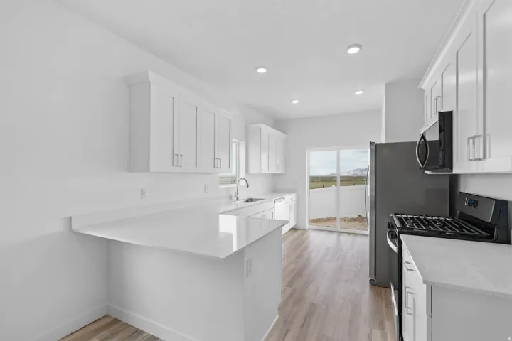 Kitchen featuring white shaker-style cabinetry, light-toned countertops, and wood-finish flooring