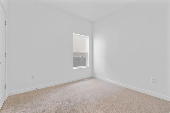 Carpeted room with white walls, a single window, and a white door