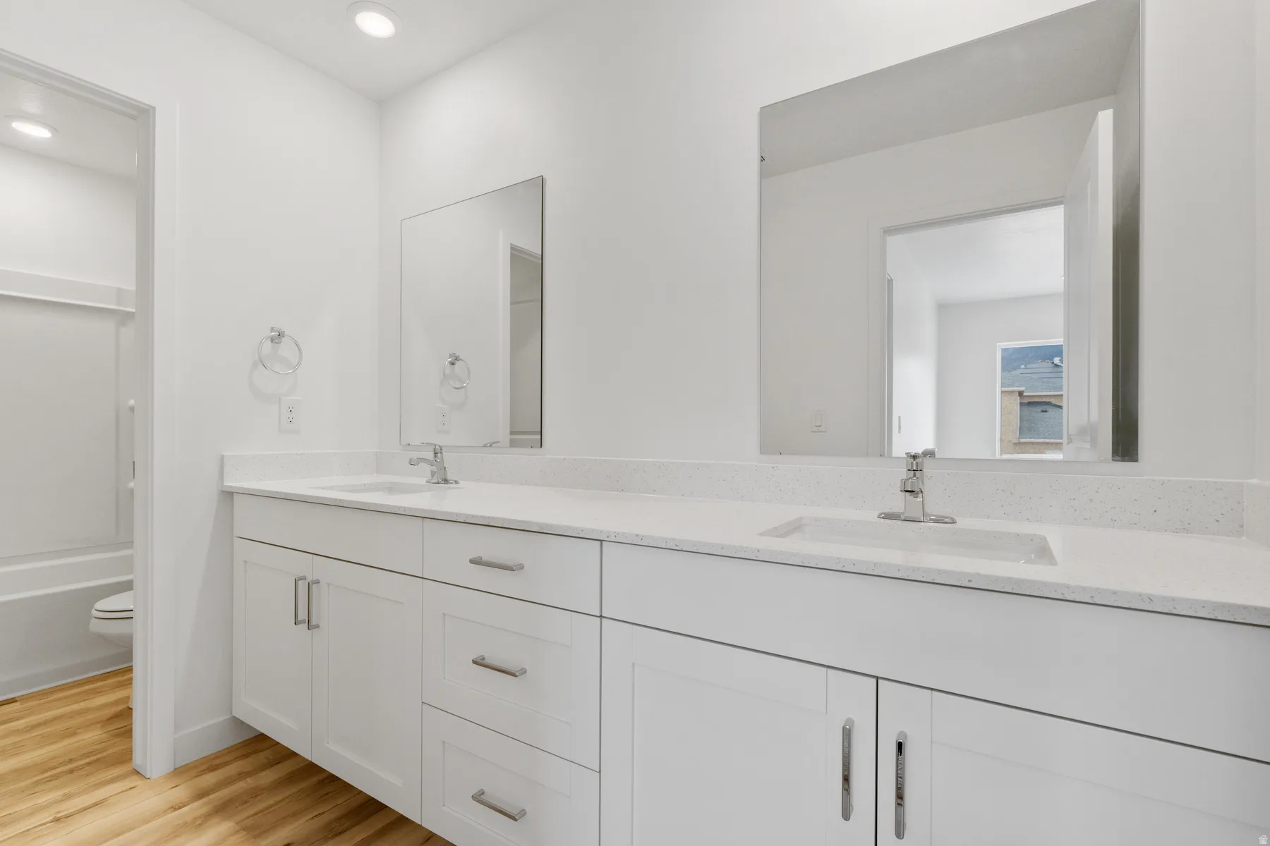 Dual vanity with white cabinetry, integrated sinks, chrome fixtures, and speckled countertops
