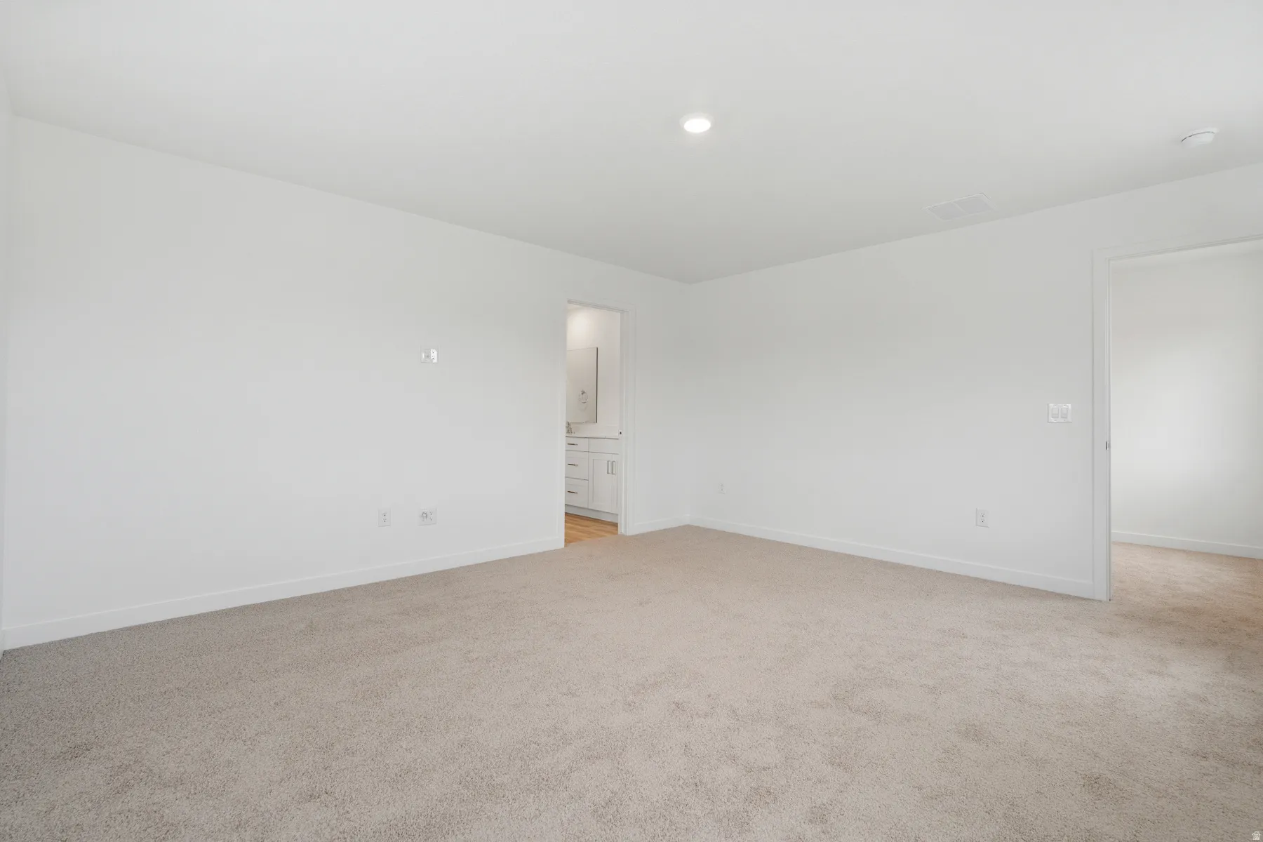 Spacious room with plush carpeting, crisp white walls, and recessed lighting