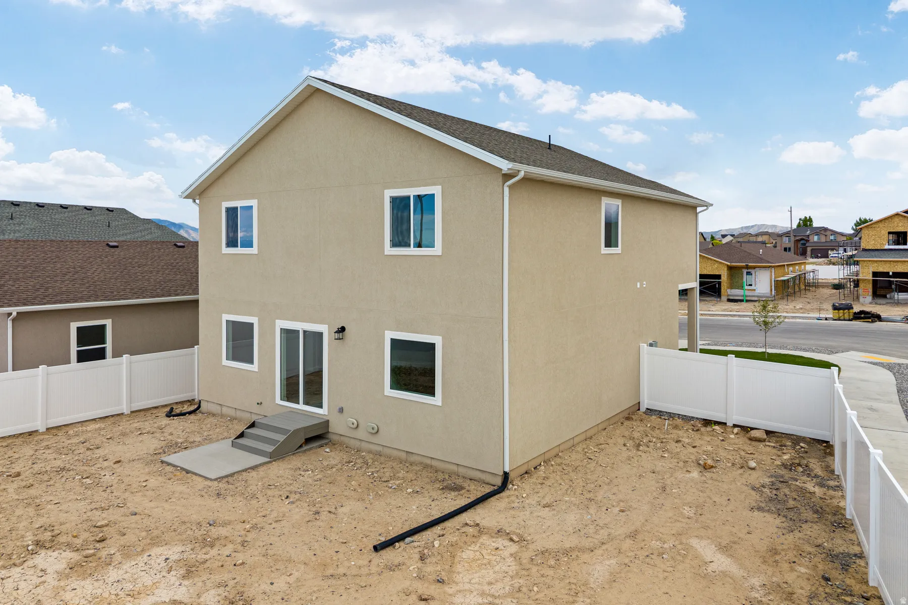 Two-story stucco exterior featuring multiple windows and a sliding glass door