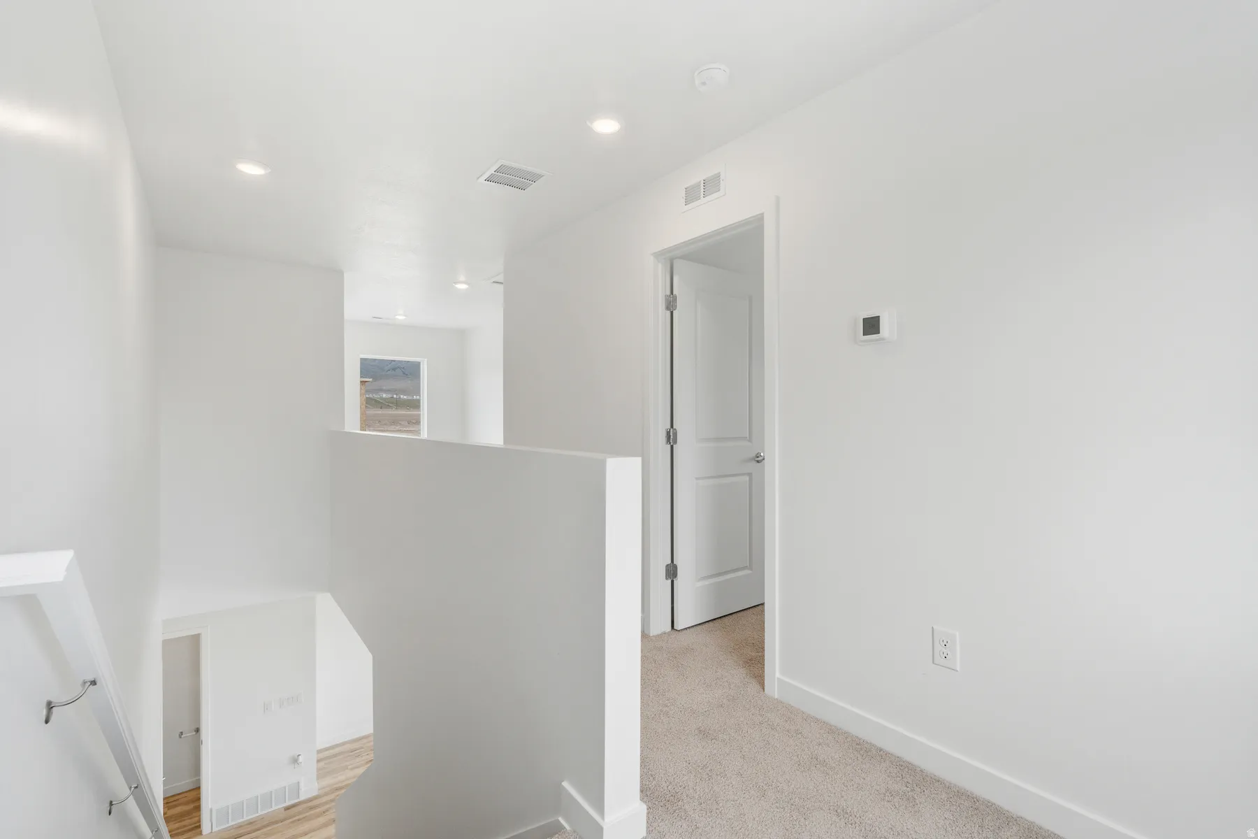 Upper-level hallway featuring neutral wall paint, recessed lighting, and soft carpet flooring