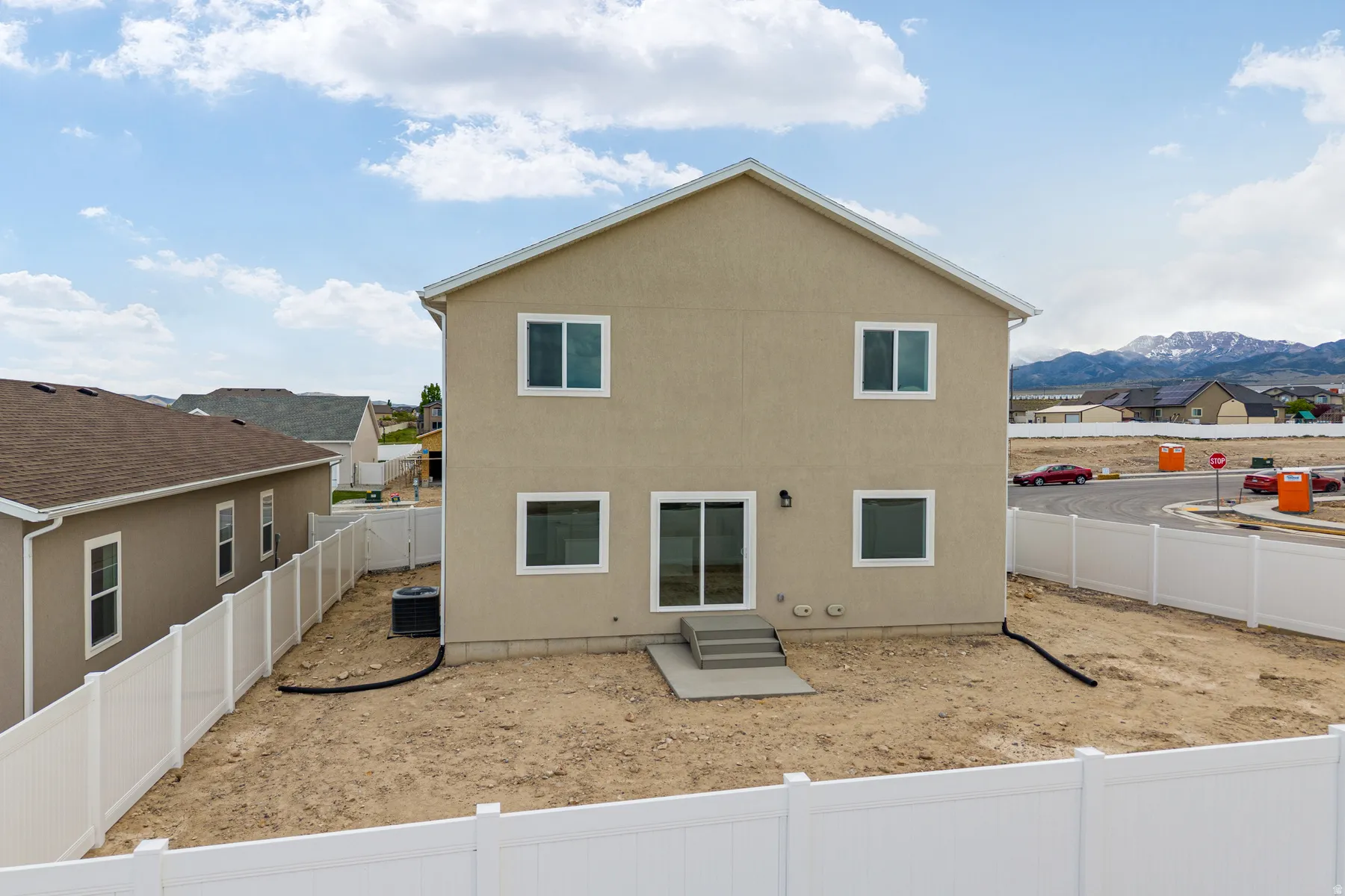 Rear exterior featuring a neutral stucco finish, white frame windows, and a sliding glass door