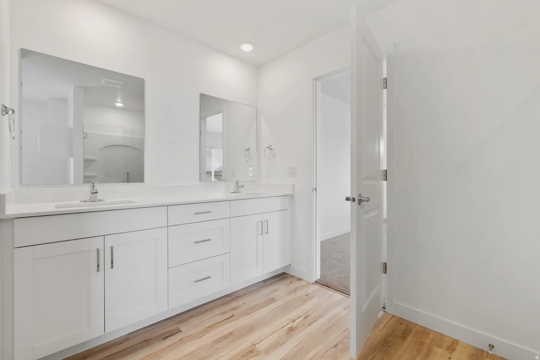 Double vanity featuring white shaker-style cabinetry, two undermount sinks, and light-toned countertops