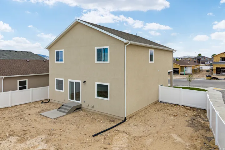 Two-story stucco exterior featuring multiple windows and a sliding glass door
