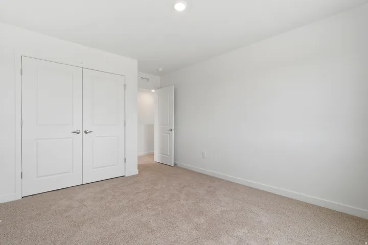 Neutral wall finishes and light brown carpet flooring