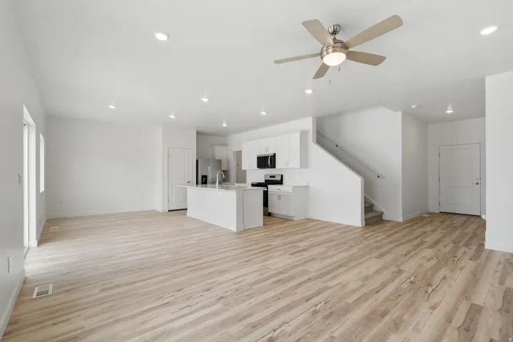Spacious open-concept living area featuring light wood-finish flooring and recessed lighting