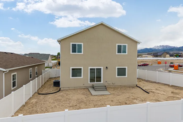 Rear exterior featuring a neutral stucco finish, white frame windows, and a sliding glass door