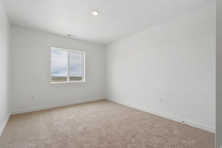 Room featuring light beige carpeting, white walls, a single recessed ceiling light, and a window with a white frame