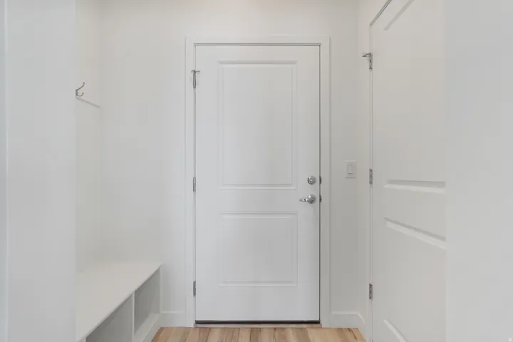 Entryway featuring a built-in bench with storage, wood-finish flooring, and white paneled doors