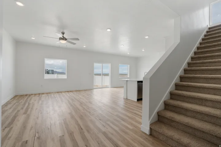 Bright open-concept living space featuring wood-finish flooring, recessed lighting, and a ceiling fan