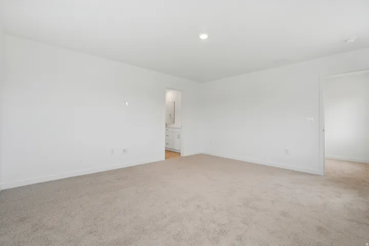 Spacious room with plush carpeting, crisp white walls, and recessed lighting