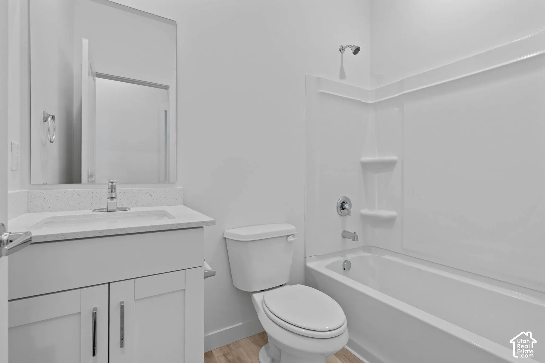 White bathroom featuring a single vanity with a solid surface countertop, an undermount sink, and a framed mirror