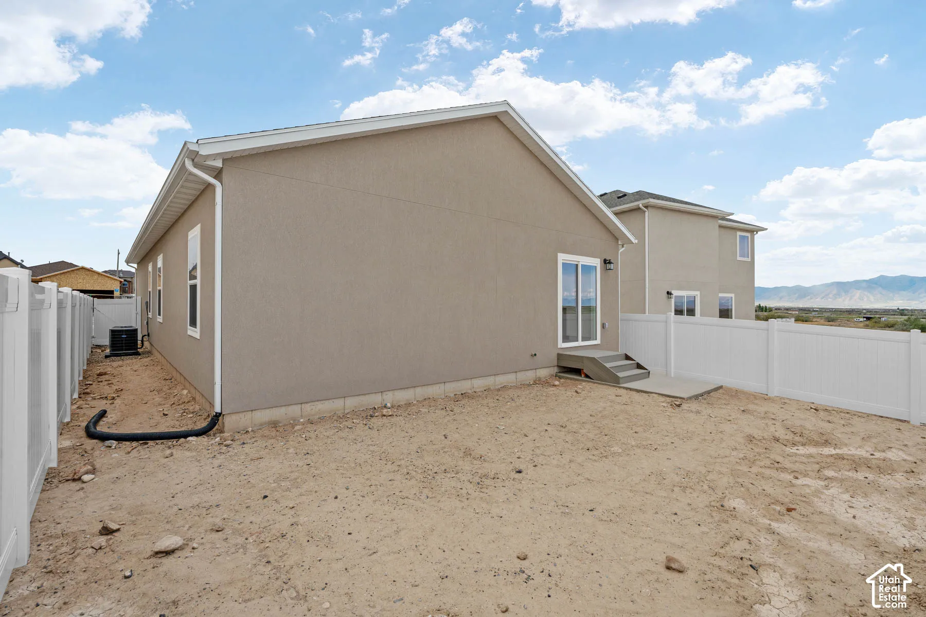 Sliding glass door, concrete patio, concrete steps, white vinyl fencing, and stucco exterior