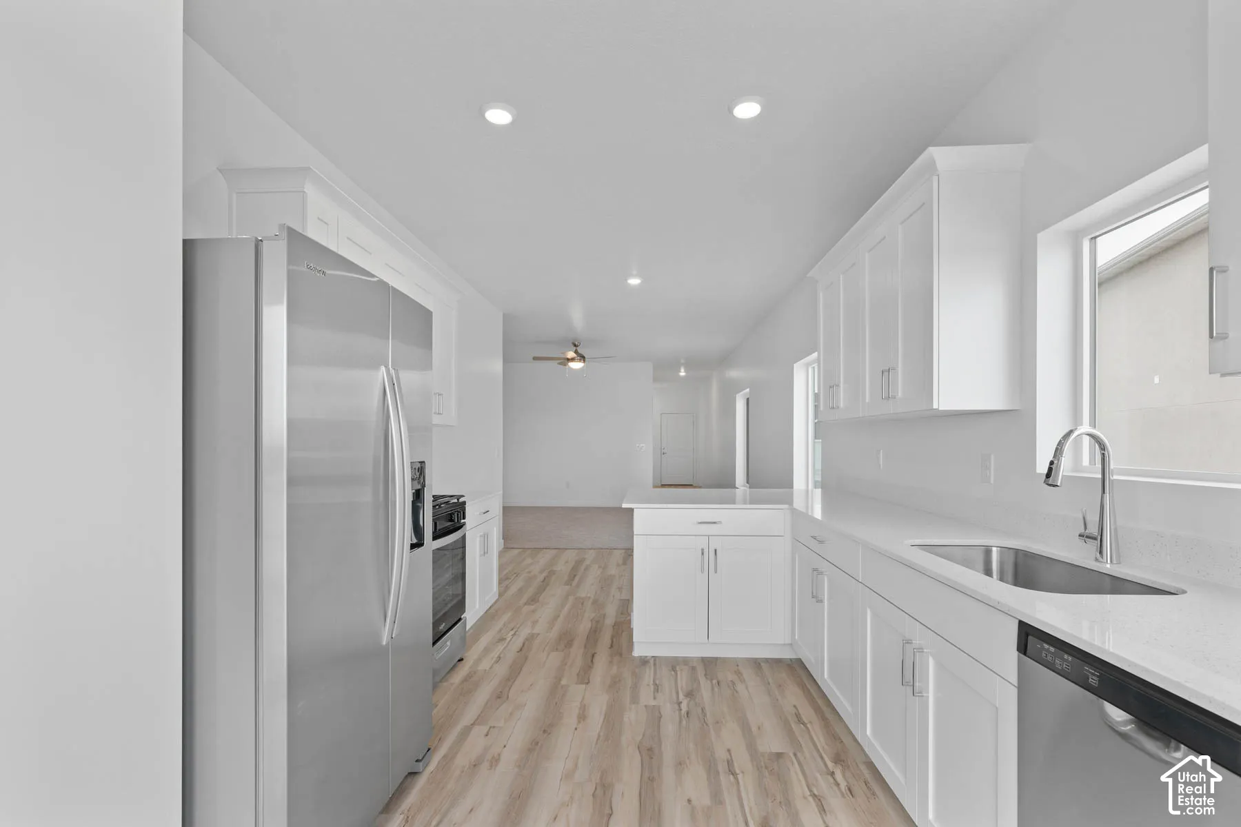 Bright kitchen featuring white cabinetry, light-toned wood-finish flooring, stainless steel appliances, and recessed lighting