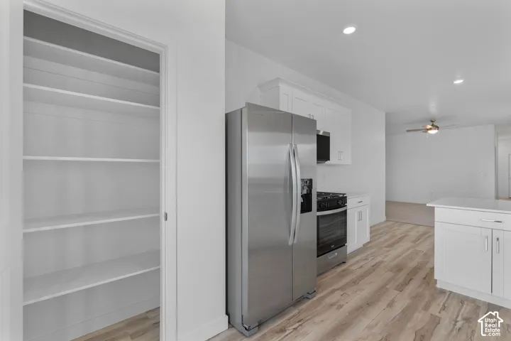 Kitchen featuring stainless steel appliances, white cabinetry, wood-finish flooring, and recessed lighting